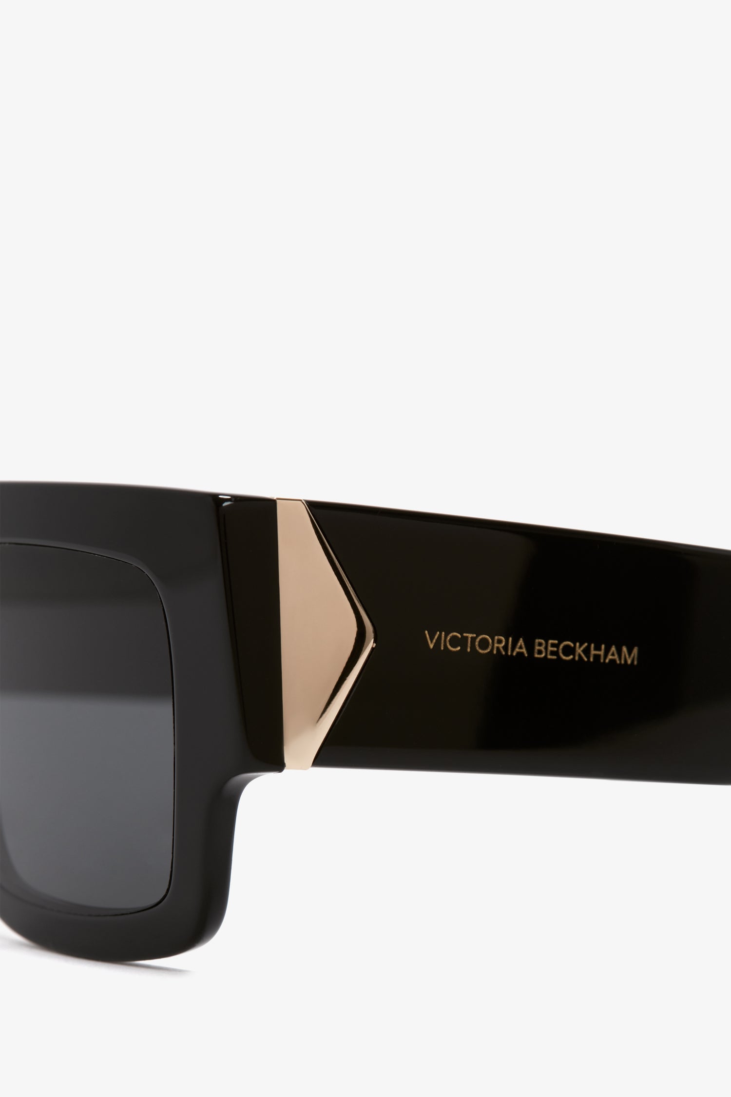 Close-up of a black Victoria Beckham V Plaque Frame Sunglasses arm with a gold logo design.