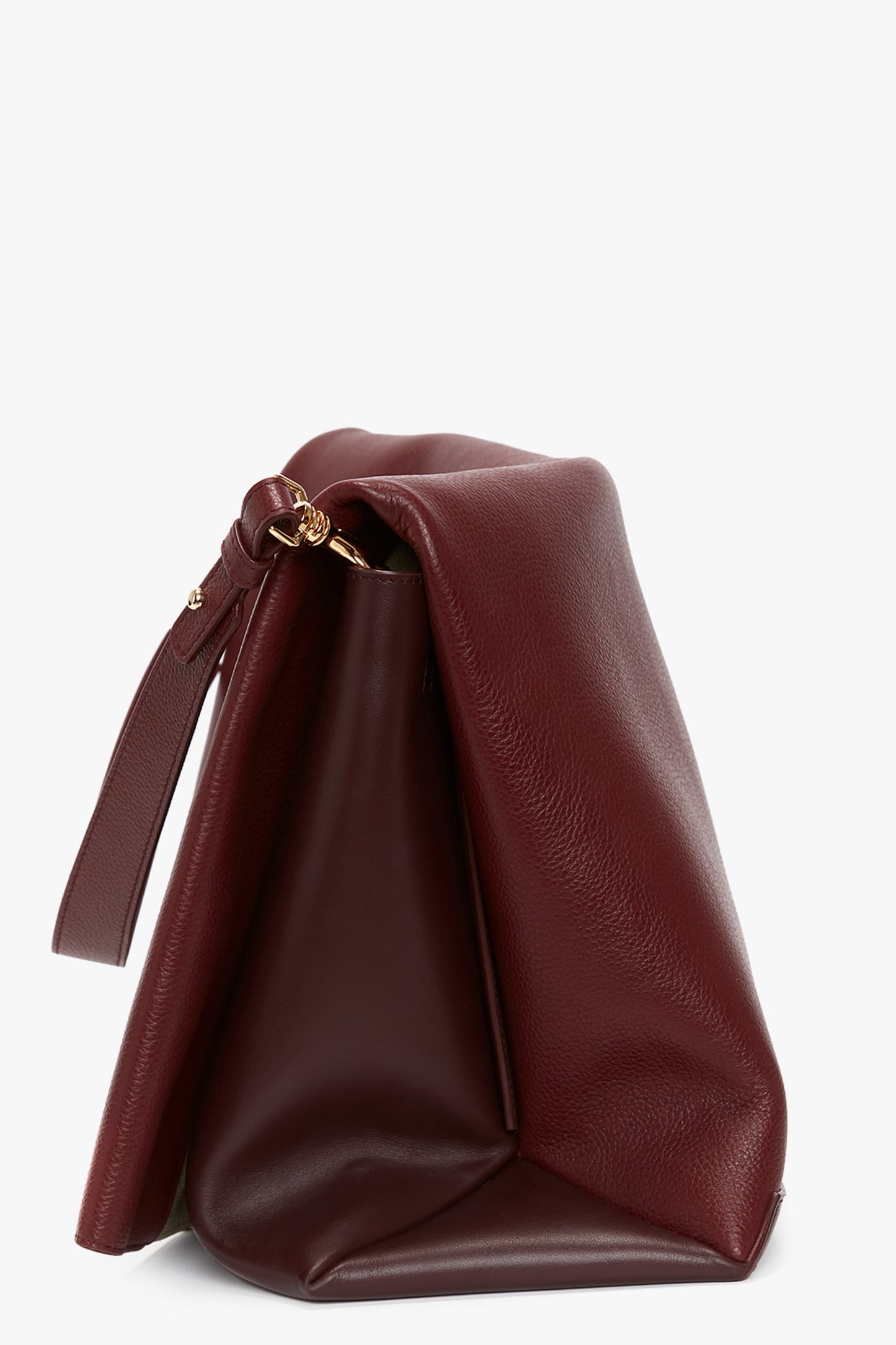 A side view of the Victoria Beckham Jumbo Chain Pouch Bag In Bordeaux Leather with a gold clasp and detachable strap detail, showing its soft, slouchy form against a plain white background.