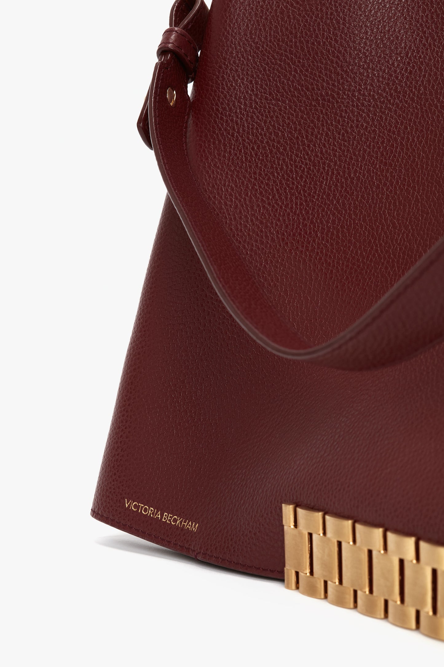 Close-up of a Jumbo Chain Pouch Bag In Bordeaux Leather featuring "Victoria Beckham" branding, a gold-colored metal detail, and a detachable strap.