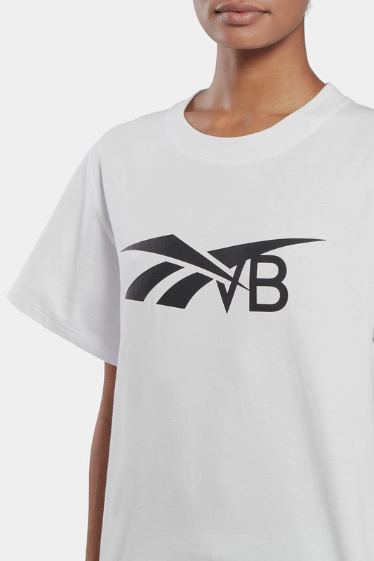 Woman wearing a sustainably sourced cotton white Reebok x VB Logo T-shirt with a black Victoria Beckham logo design on the chest.