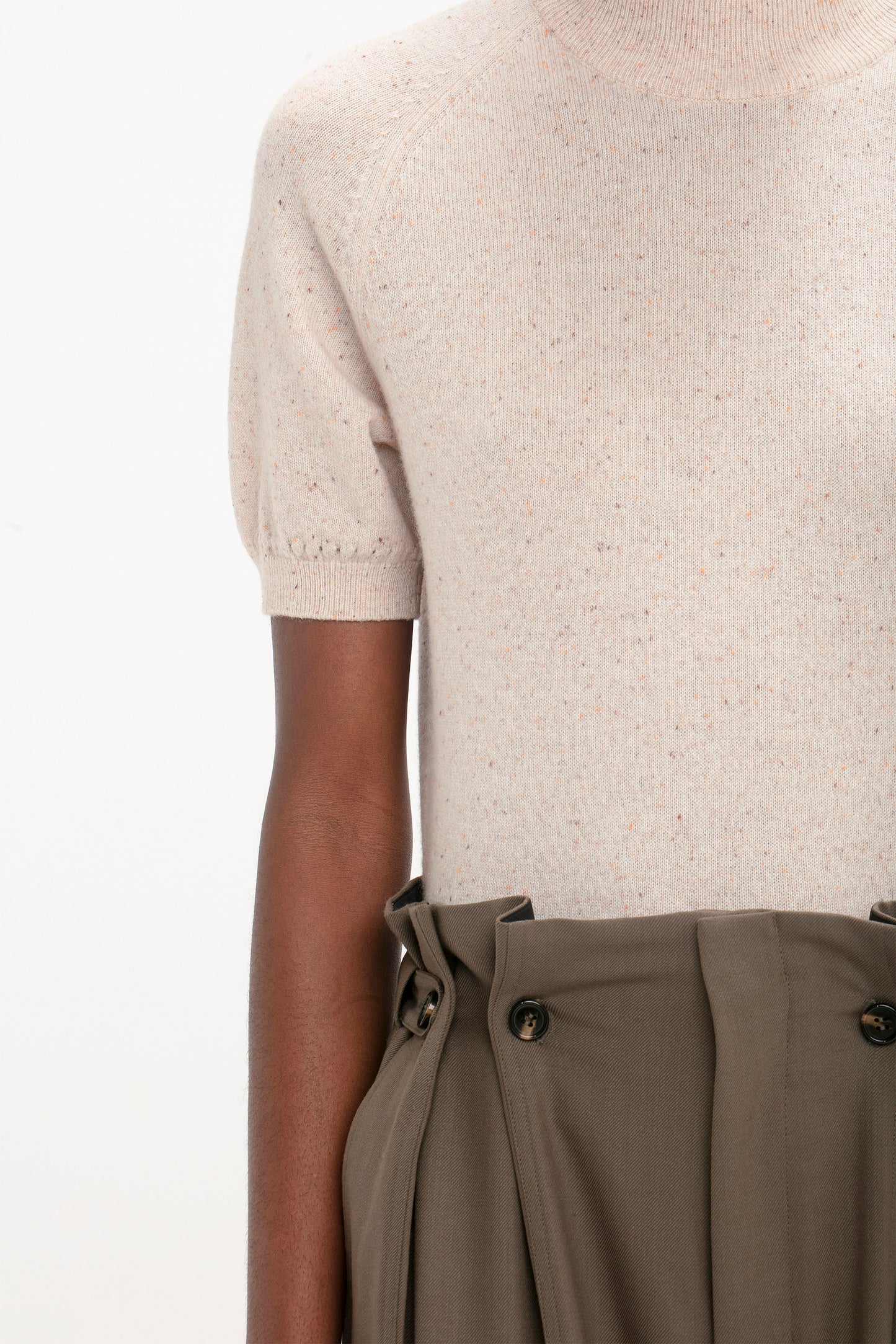A person wearing a Victoria Beckham Short Sleeve Top In Nougat with high-waisted khaki trousers with button details.