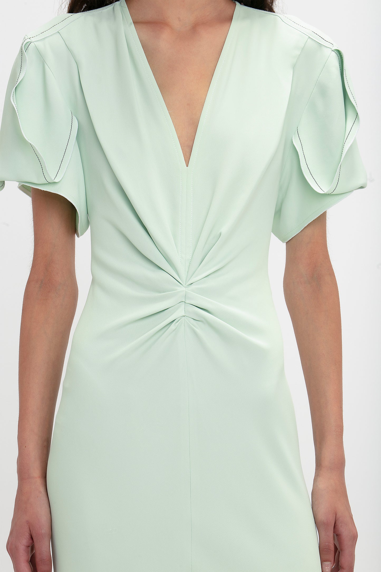 A close up of a woman's body wearing a Victoria Beckham Gathered V-Neck Midi Dress In Jade.