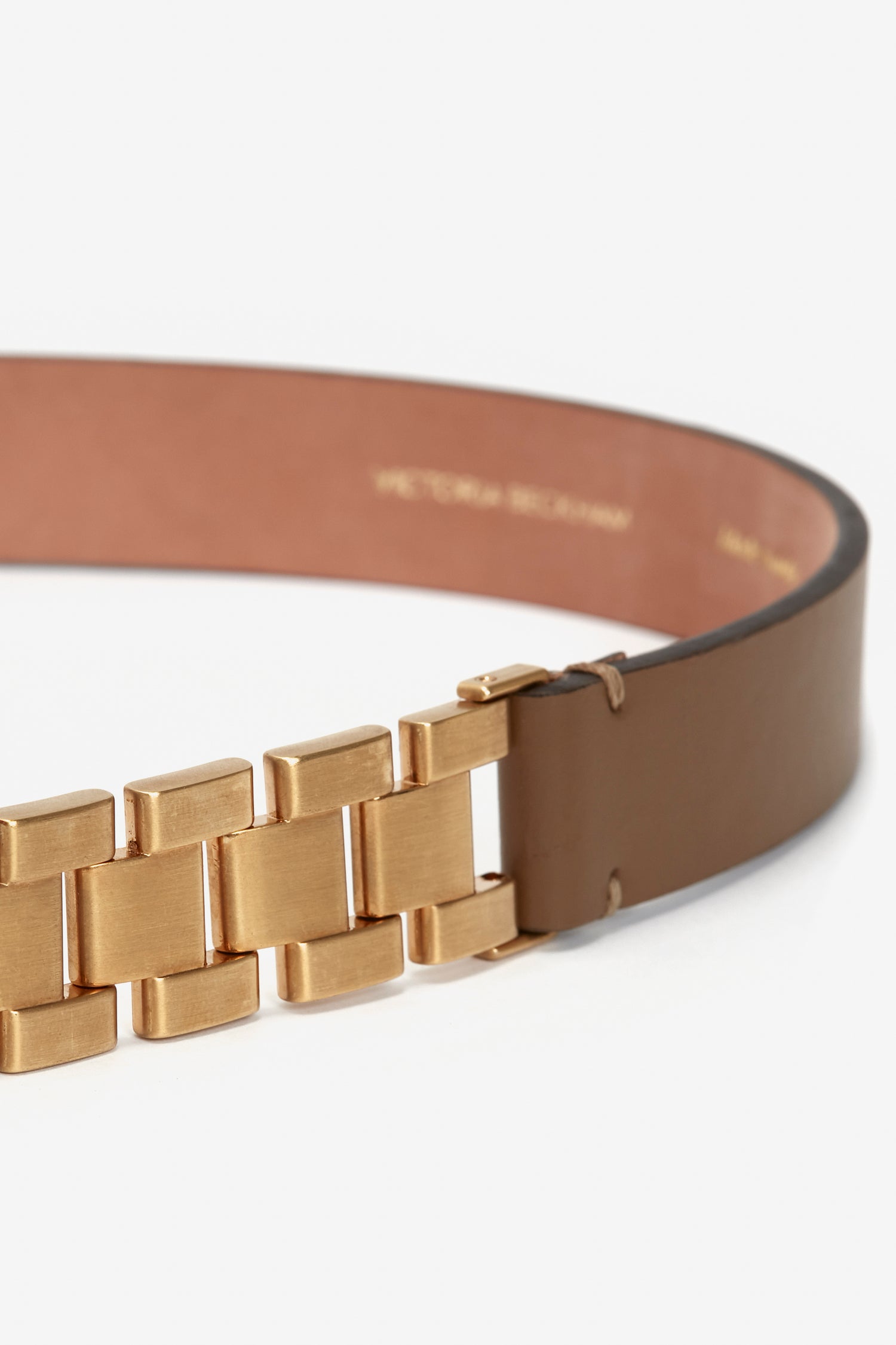 Close-up of a Victoria Beckham UK Watch Strap Detail Belt in Khaki-Brown featuring a gold metallic link buckle, isolated on a white background.