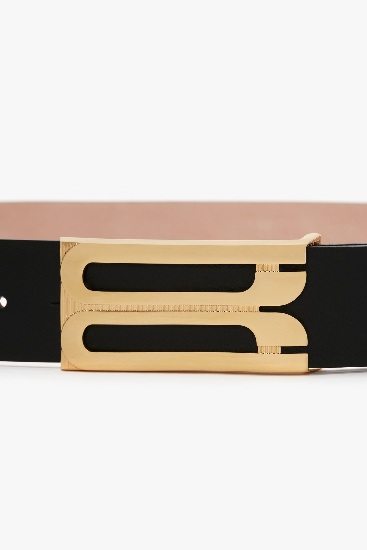 A close-up of an Exclusive Jumbo Frame Belt In Navy Leather by Victoria Beckham, showcasing its black smooth calf leather strap and gold hardware buckle with a sleek, modern design.