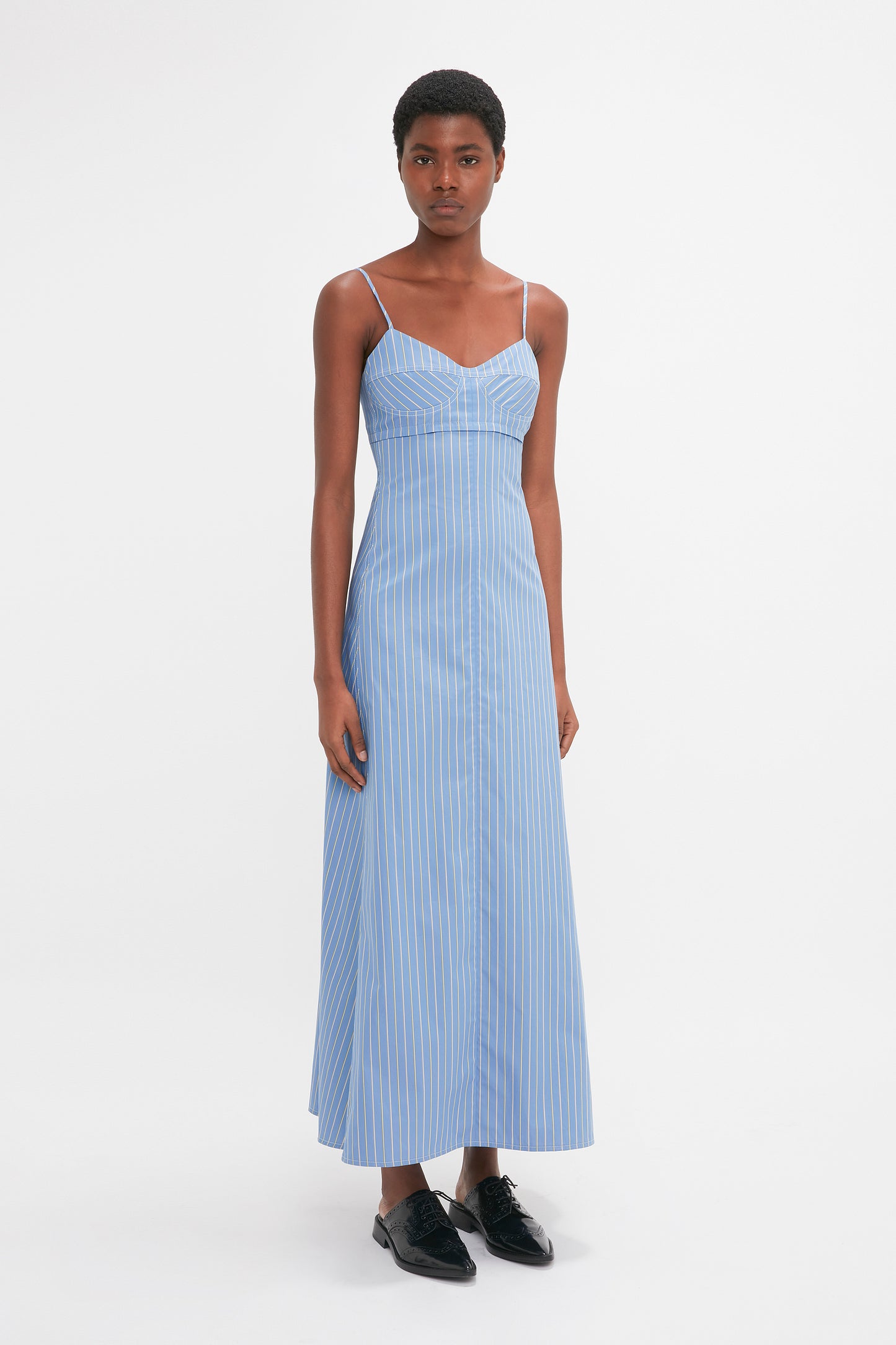 Person wearing a Victoria Beckham Cami Fit And Flare Midi In Steel Blue, paired with black shoes, standing against a plain white background.