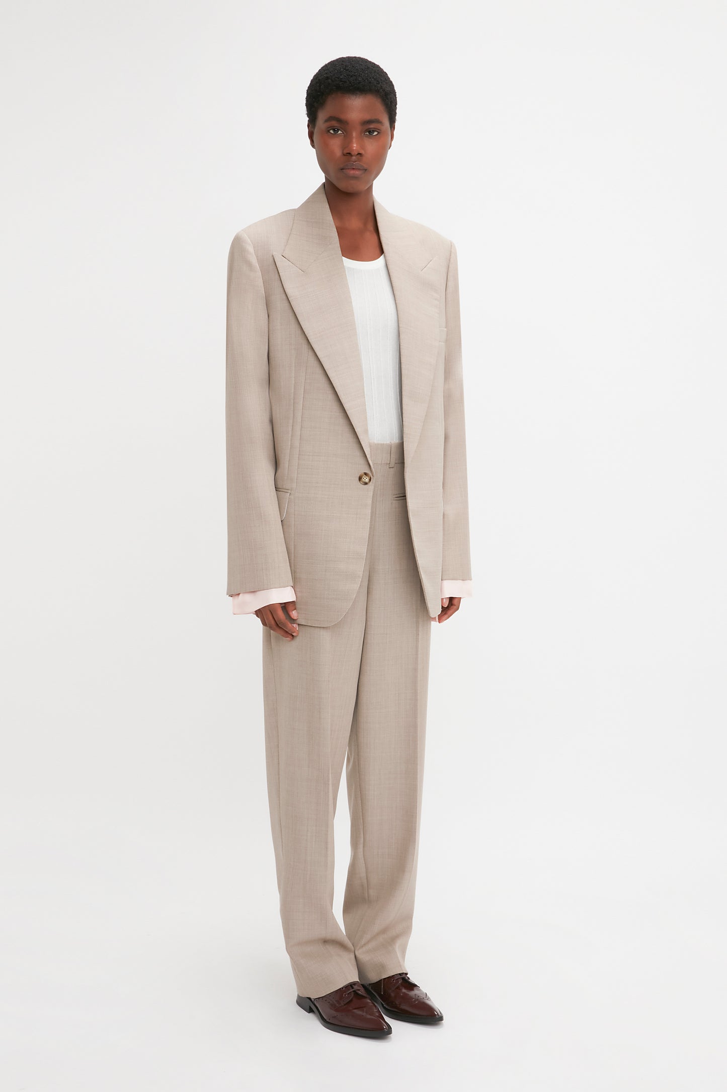 A woman in a Darted Sleeve Tailored Jacket In Sesame by Victoria Beckham, featuring darted sleeves and contemporary detailing.