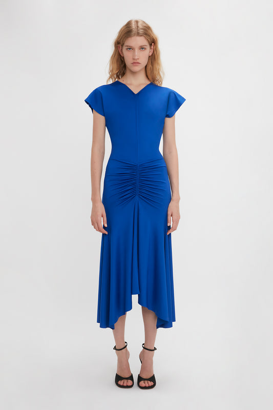 A woman in a Sleeveless Rouched Jersey Dress In Royal Blue by Victoria Beckham, standing against a plain white background.