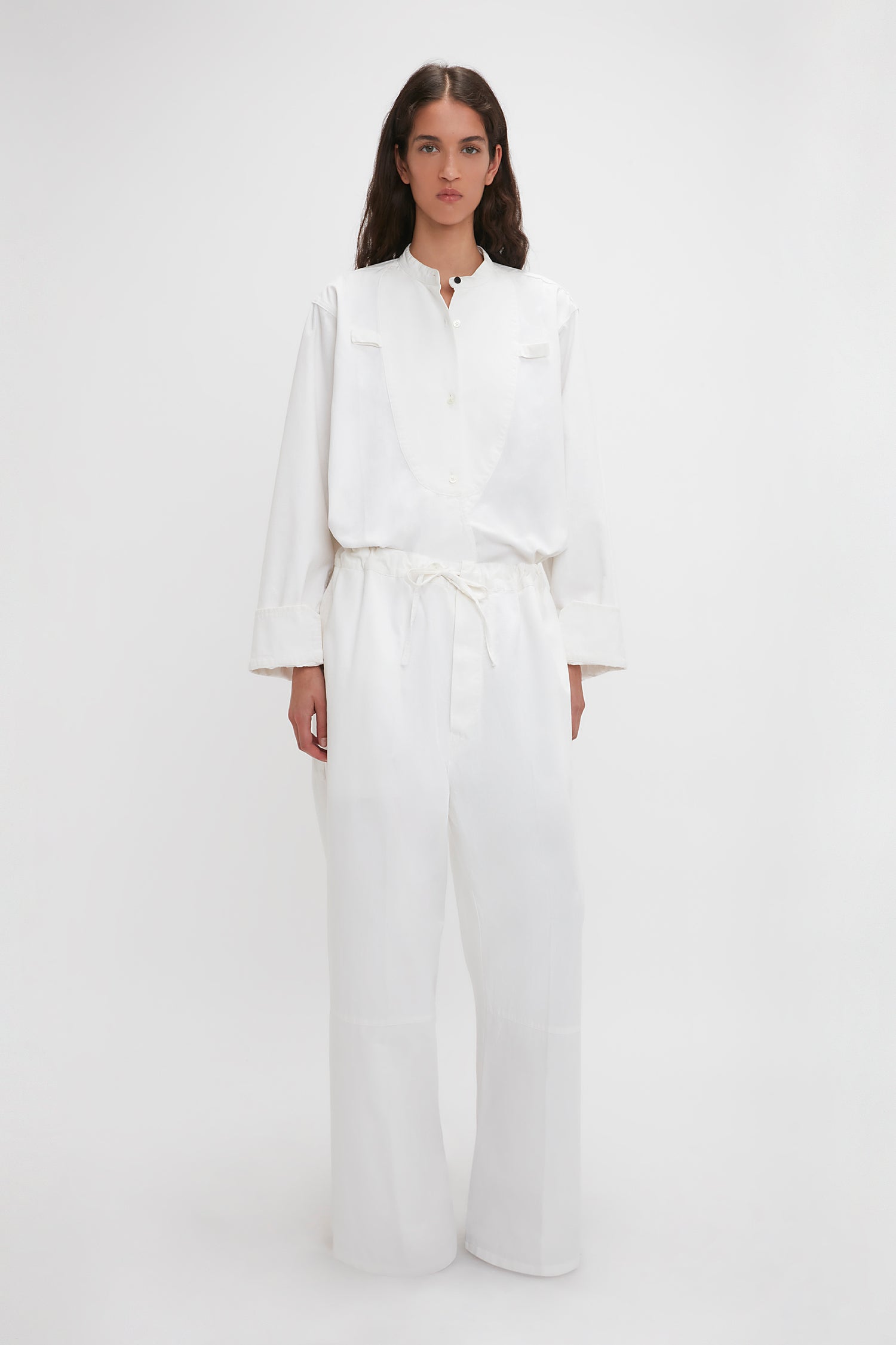 A woman in Victoria Beckham's Drawstring Pyjama Trouser In Washed White stands against a plain background, looking directly at the camera.