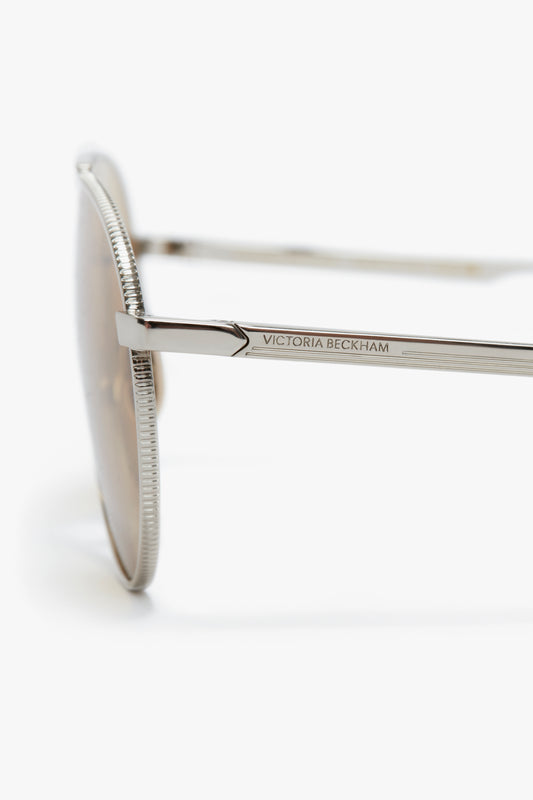 Close-up of the side of a Victoria Beckham branded V Metal Pilot sunglasses in Silver-Brown showing the intricate design on the temple.