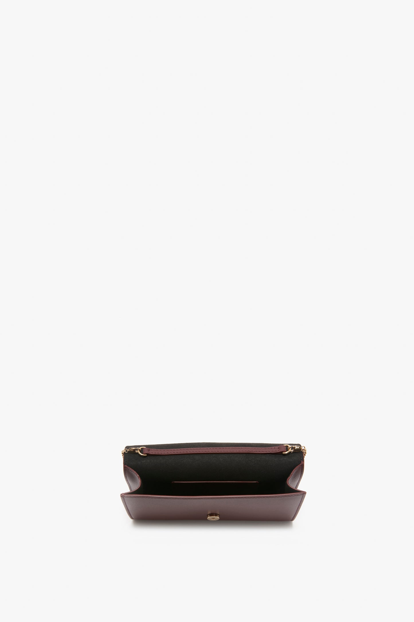 A top-view image of an open, empty, burgundy leather Wallet On Chain In Burgundy Leather by Victoria Beckham with gold zipper detailing and a single interior compartment against a white background, featuring subtle palmellato leather texture.