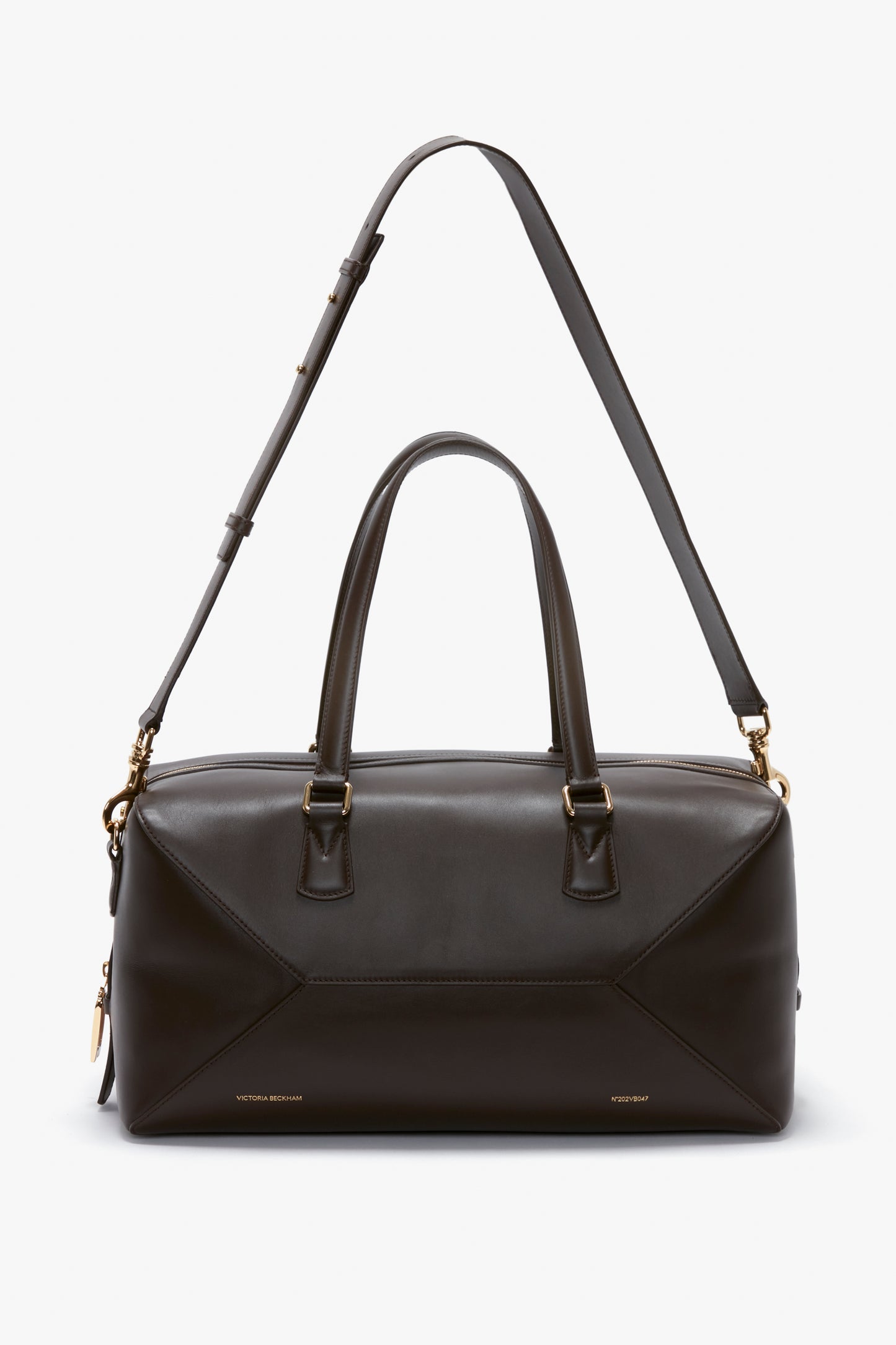 A Medium Gym Bag In Chocolate Brown by Victoria Beckham with gold hardware, featuring two top handles and an adjustable shoulder strap, inspired by the stylish designs of Victoria Beckham.