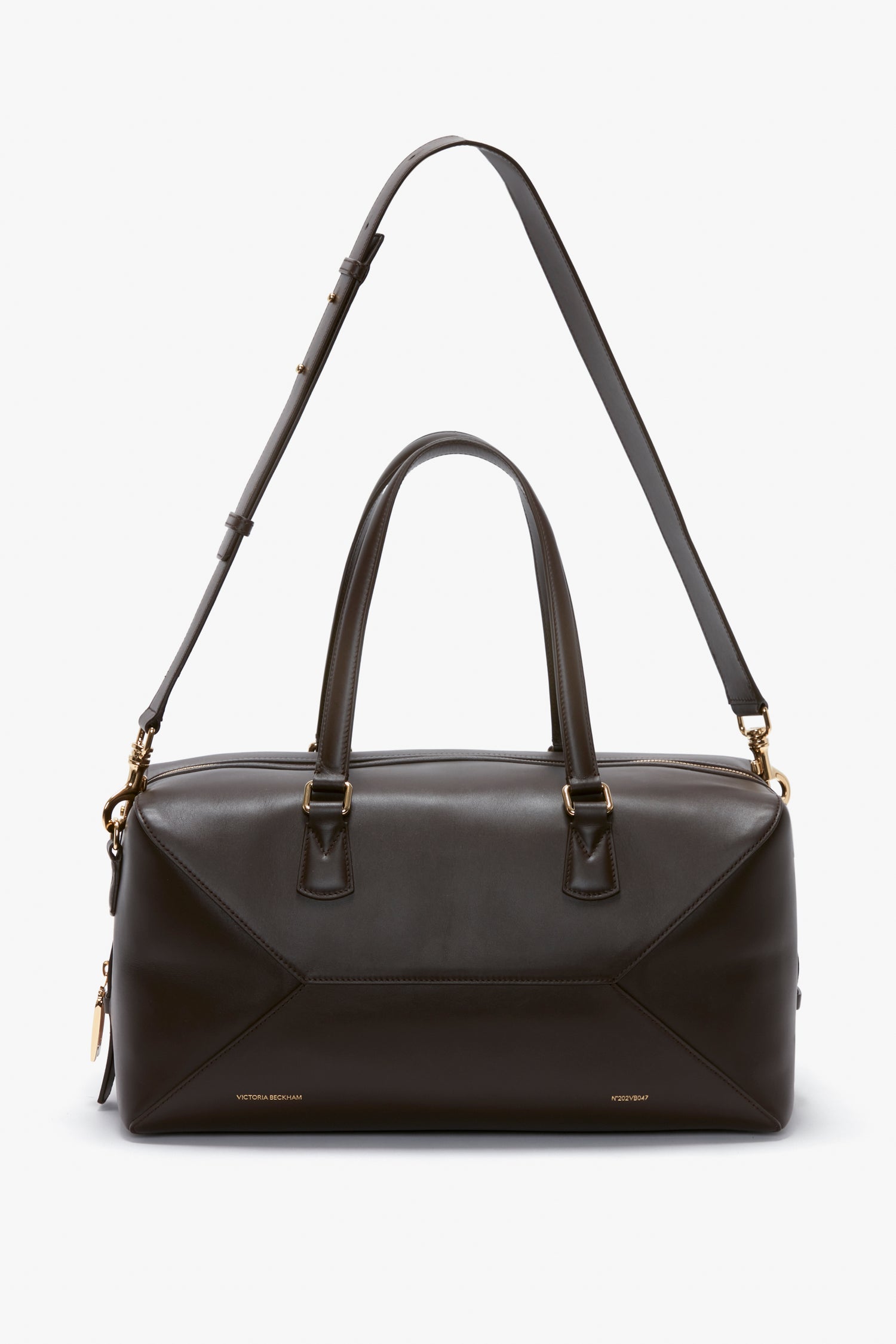 A Medium Gym Bag In Chocolate Brown by Victoria Beckham with gold hardware, featuring two top handles and an adjustable shoulder strap, inspired by the stylish designs of Victoria Beckham.