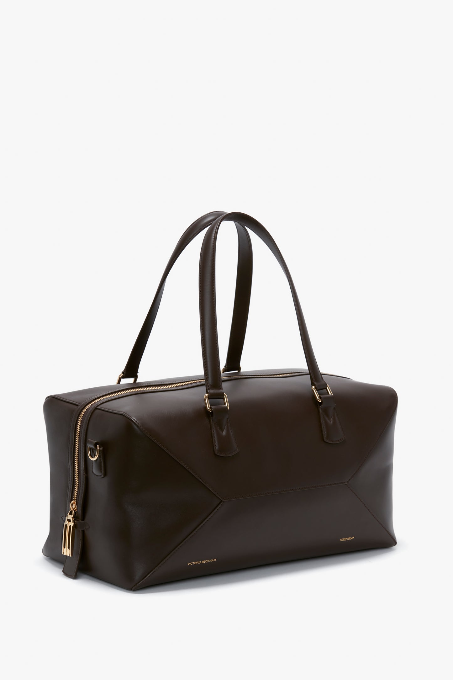 A Victoria Beckham Medium Gym Bag In Chocolate Brown with two handles, a gold zipper, and geometric panel details.