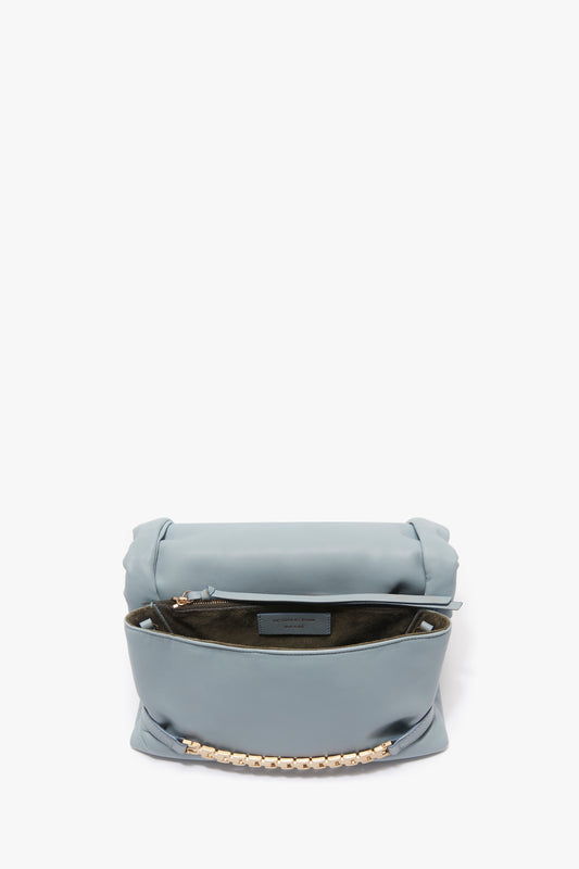 Light blue Puffy Chain Pouch with strap in ice leather by Victoria Beckham, displayed open to reveal an inner compartment, against a white background.