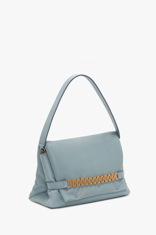 Light blue Puffy Chain Pouch With Strap In Ice Leather handbag by Victoria Beckham, with a golden metallic brand logo on the front, isolated on a white background.