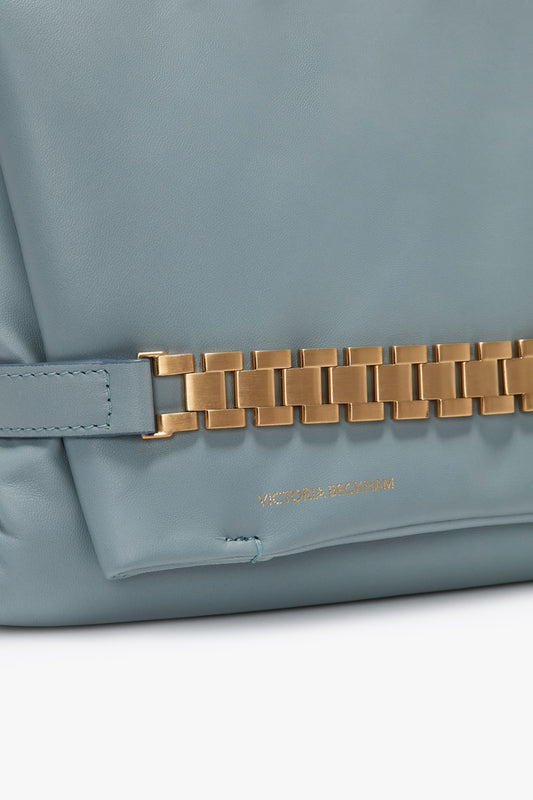 Close-up of a light blue Victoria Beckham Puffy Chain Pouch With Strap In Ice Leather with a distinctive signature gold chain detail and visible brand label.