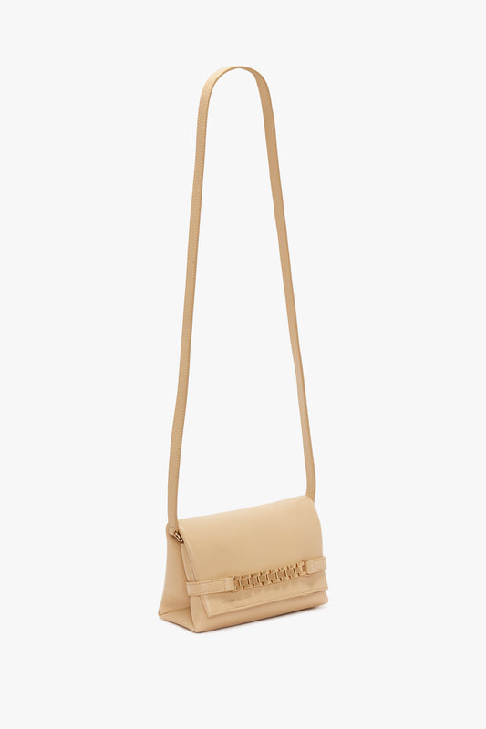 A Victoria Beckham beige leather crossbody shoulder bag with a slim strap and subtle embossed branding on the front.