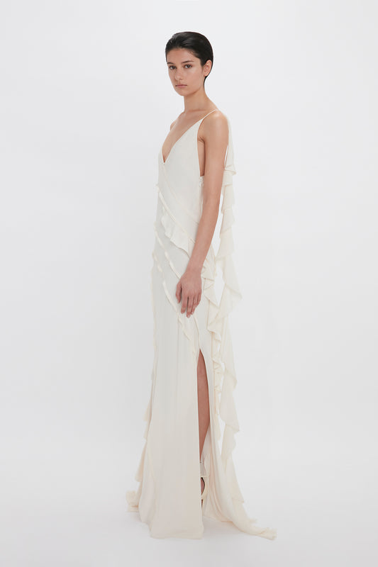 A woman in a Victoria Beckham Exclusive Asymmetric Bias Frill Dress In Ivory gown posing against a white background.