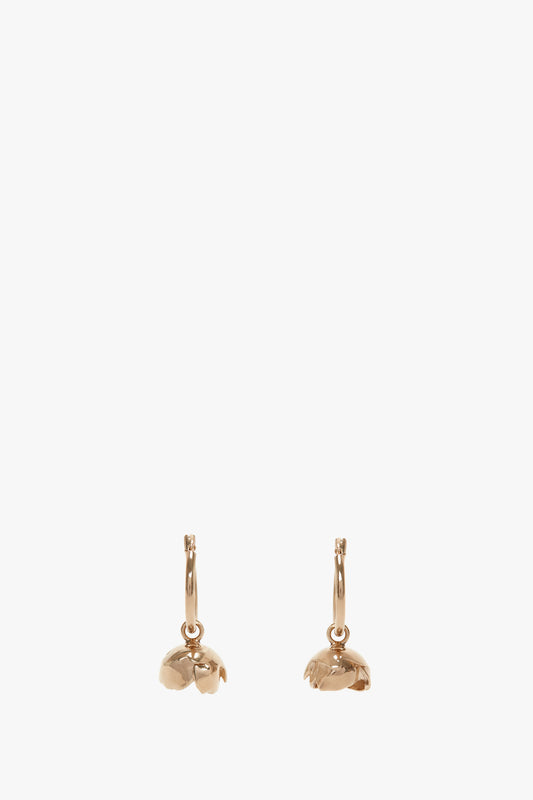 Two Exclusive Camellia Flower Hoop Earrings In Gold with dangling mushroom charms against a white background by Victoria Beckham.