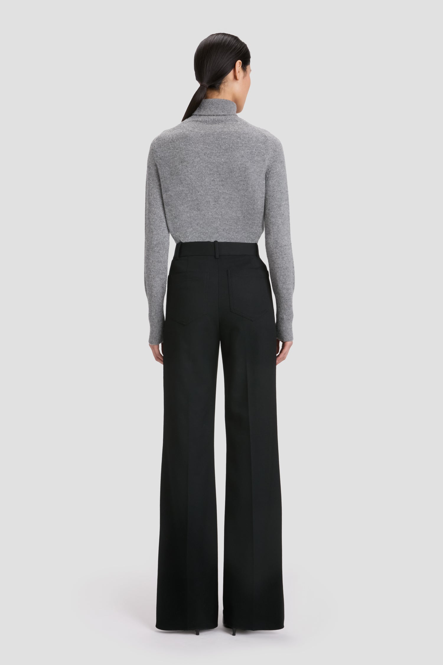 A person stands facing away, wearing Victoria Beckham’s BAO TEST - Jeans Short against a plain background.