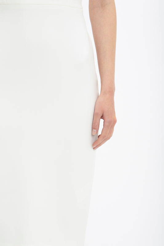 Close-up of a woman's side, focusing on her arm resting along her Victoria Beckham fitted T-shirt dress, emphasizing the simplicity of the outfit and manicured nails.