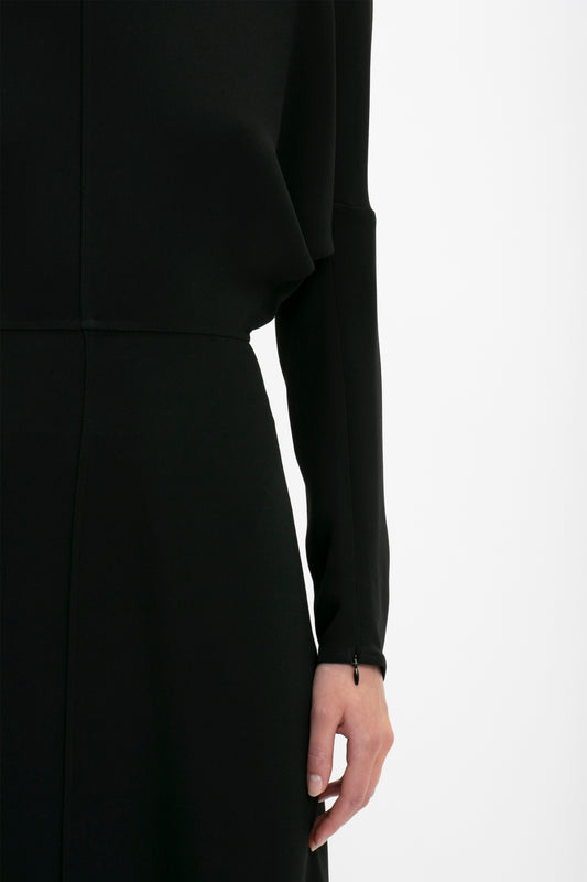 A close-up image capturing a woman's side from shoulder to hip, wearing a Victoria Beckham Dolman Midi Dress in Black.