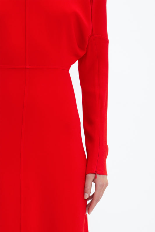 Close-up of a person wearing a bright red Victoria Beckham Dolman Midi Dress, focusing on the sleeve and waist detail. The background is plain white.