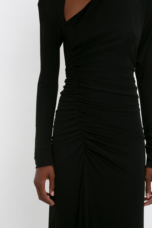 Close-up of a woman in a Victoria Beckham Slash-Neck Ruched Midi Dress In Black, focusing on the detail of the fabric and design.
