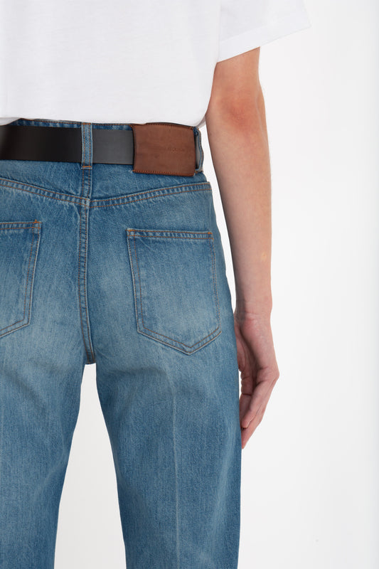 Rear view of a person wearing Victoria Beckham distressed "Julia Jean In Broken Vintage Wash" jeans and a white t-shirt, with a brown and black belt visible.