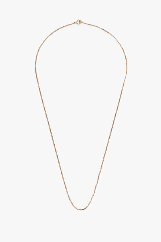 A delicate, fine chain gold-plated brass necklace with a small clasp, inspired by the elegance of Victoria Beckham, shown on a white background.
