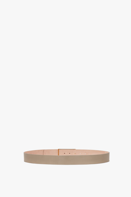 Exclusive Jumbo Frame Belt In Beige Leather by Victoria Beckham, with a simple, sleek design featuring a traditional buckle with holes for adjustment and gold hardware, displayed against a plain white background.