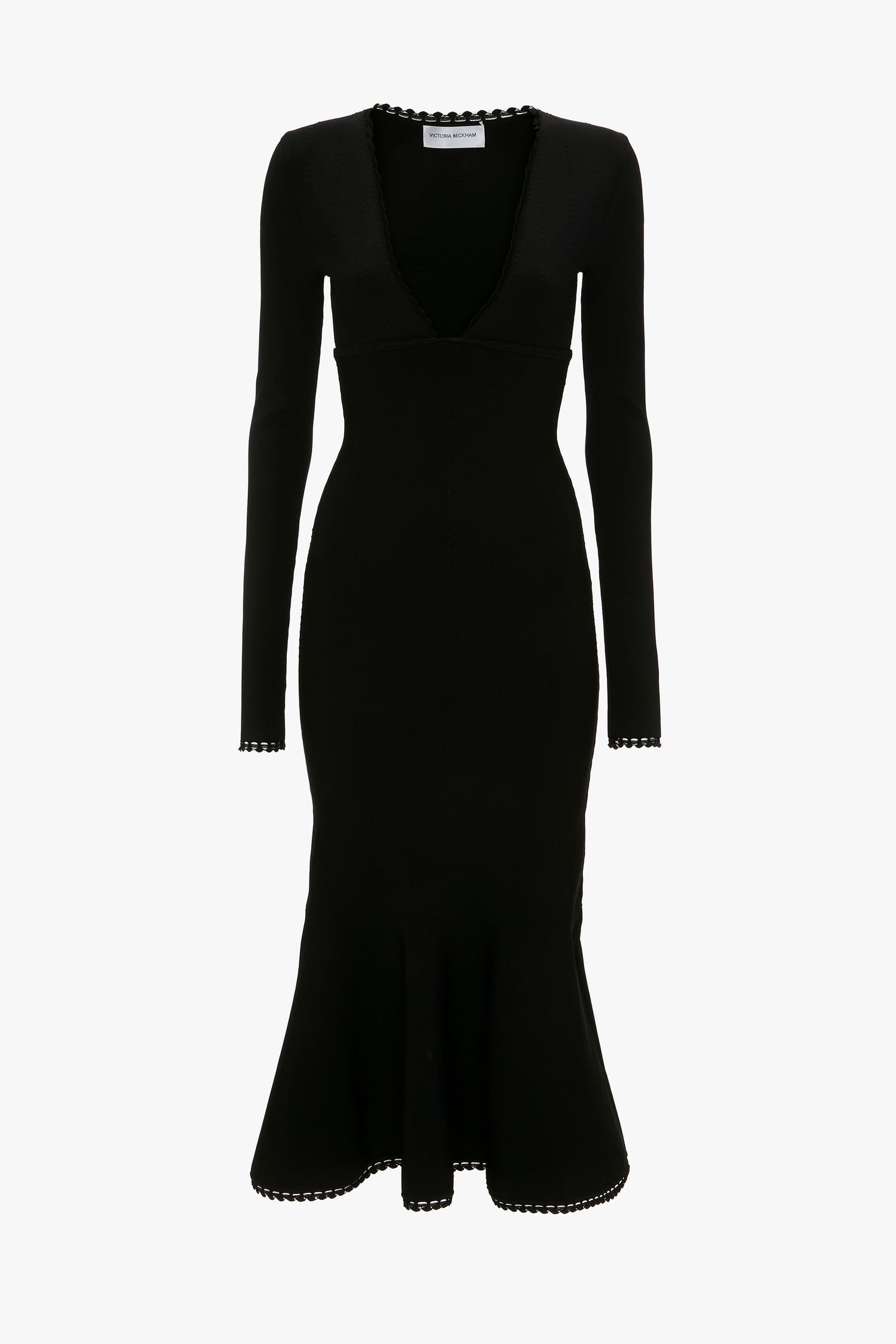 A Victoria Beckham VB Body Long Sleeve V Neck Dress In Black with a mid-length hem that features scalloped edges on the cuffs, hem, and plunging V-neck.