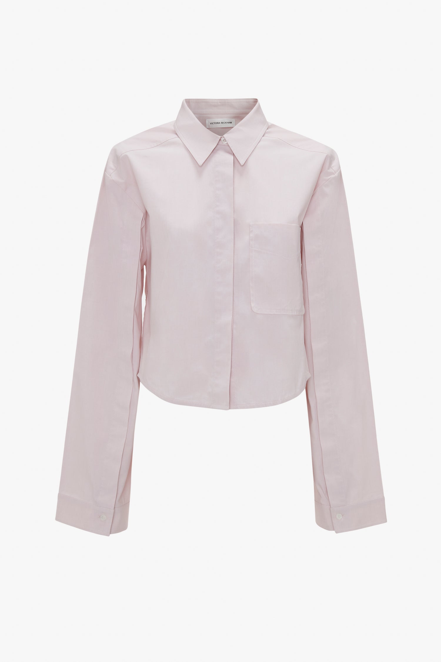 A Victoria Beckham Button Detail Cropped Shirt In Rose Quartz, featuring long sleeves, a pointed collar, and a front pocket, is displayed against a white background.
