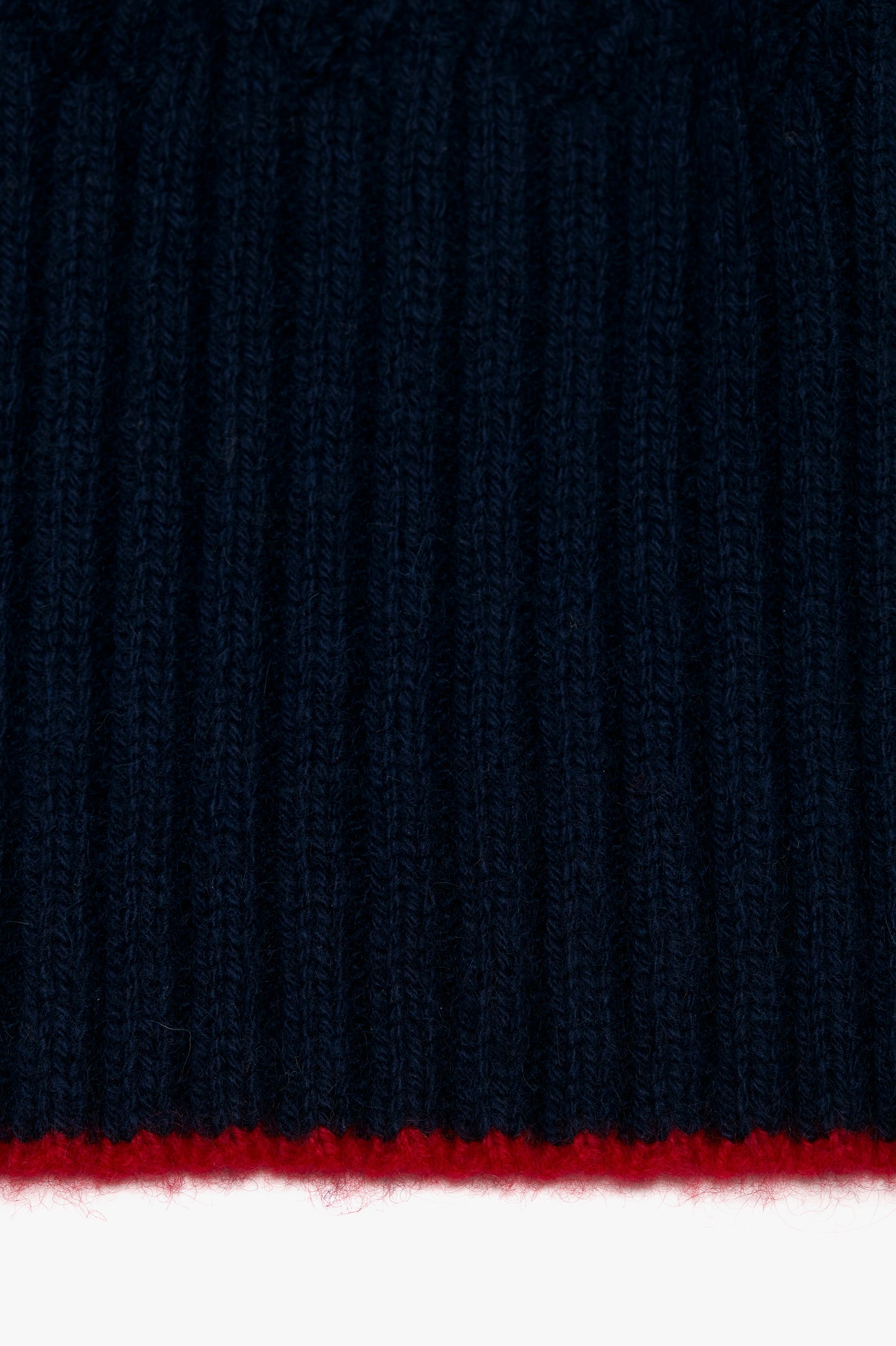 Close-up of a Victoria Beckham Exclusive Logo Patch Scarf In Navy with a thin horizontal red stripe at the bottom edge.