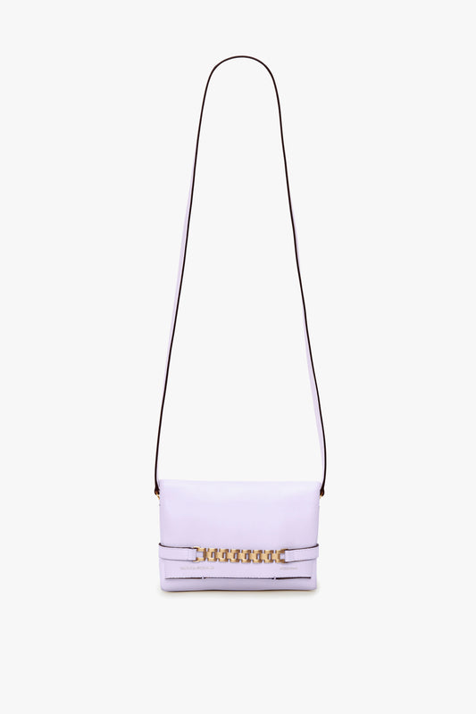 A Victoria Beckham Exclusive Mini Chain Pouch Bag With Long Strap In Lilac Leather with a long, thin detachable strap and gold chain detailing on the front.