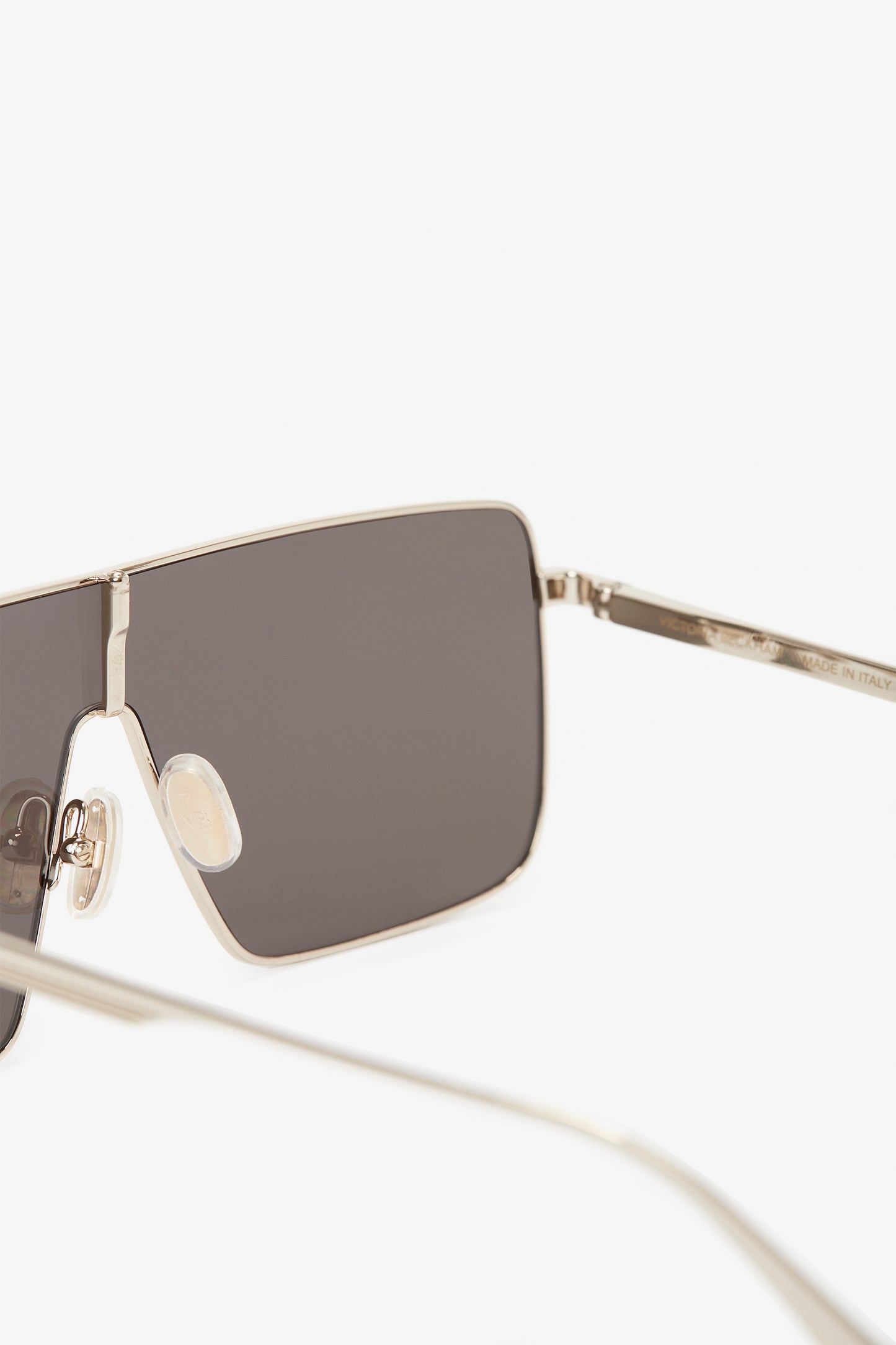 Close-up of Rectangular Visor In Gold-Smoke with a sleek silver metal frame, slightly angled to the left, featuring the Victoria Beckham logo.