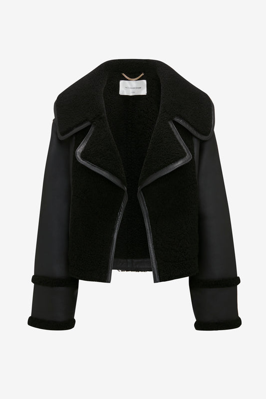 Victoria Beckham's Shearling Jacket in Black with wide lapels and contrasting leather sleeves, displayed on a white background.