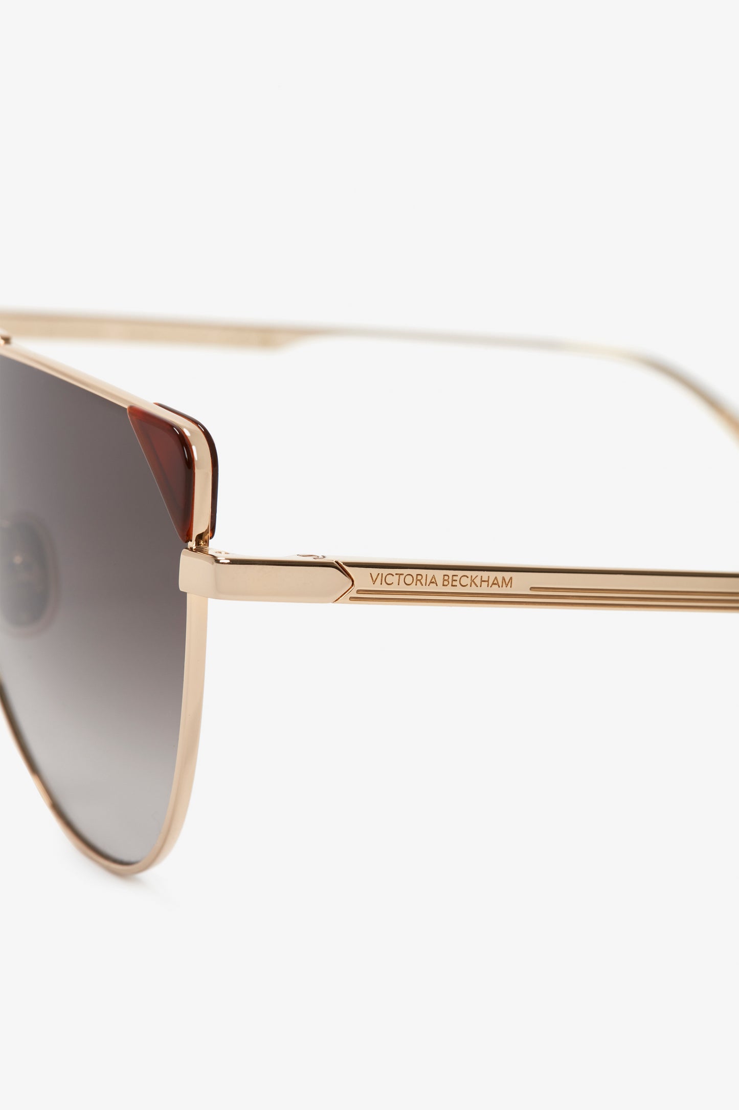 Close-up of V-Line Aviator In Gold Blonde Havana sunglasses with gold metal frames and caramel gradient lenses. The temple arm displays "Victoria Beckham" branding.