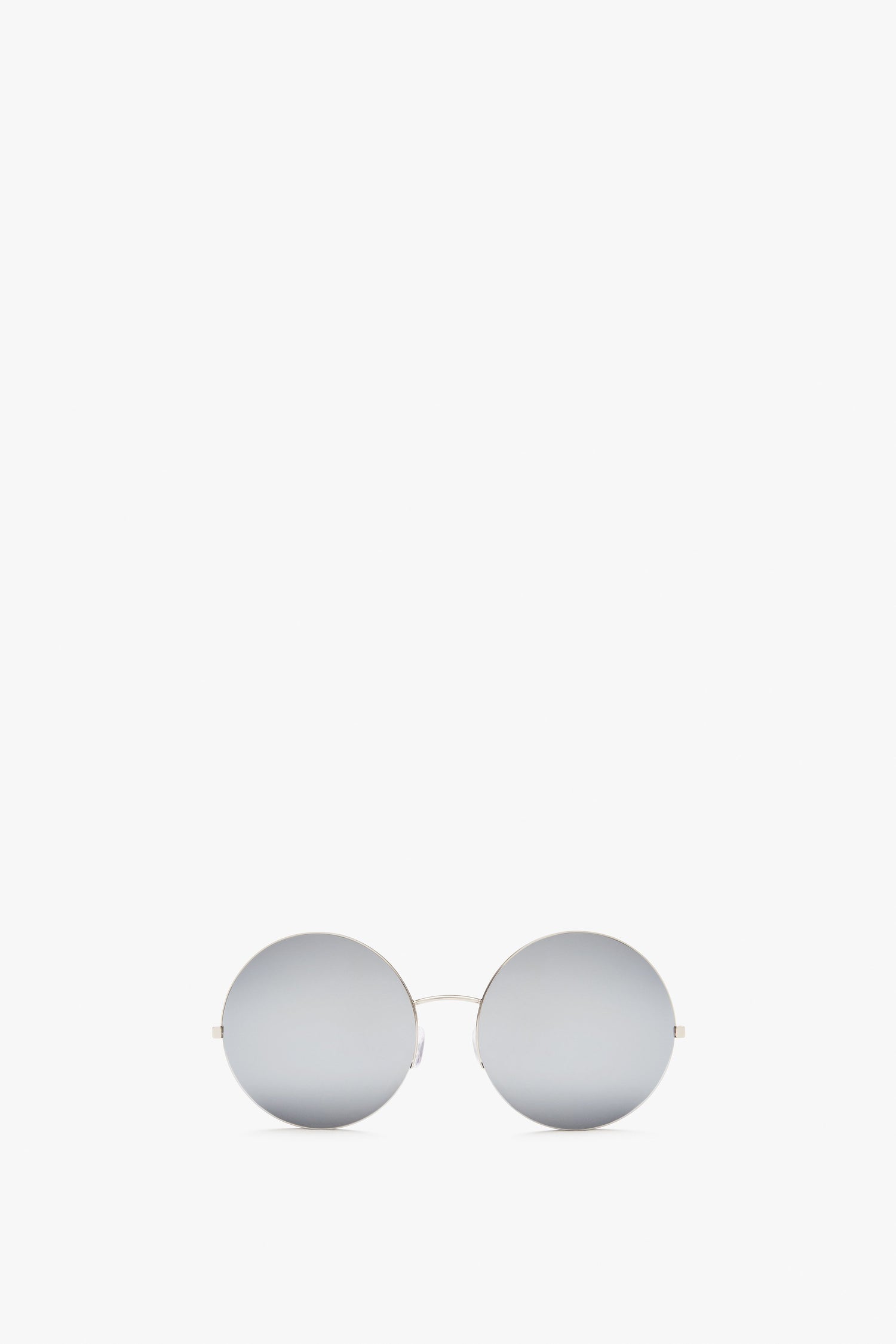 Pair of Victoria Beckham Supra Round, silver-mirrored sunglasses with thin, metallic frames and a minimalist design featuring Zeiss certified lenses for UV protection, positioned against a plain white background.