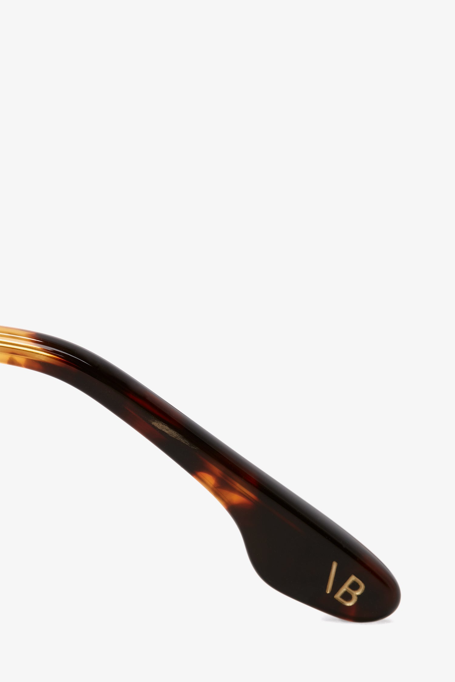 Close-up of a Dark Havana tortoise acetate eyeglass arm from the Guilloche Frame Opticals In Dark Havana by Victoria Beckham, with the initials "IB" engraved in gold letters.