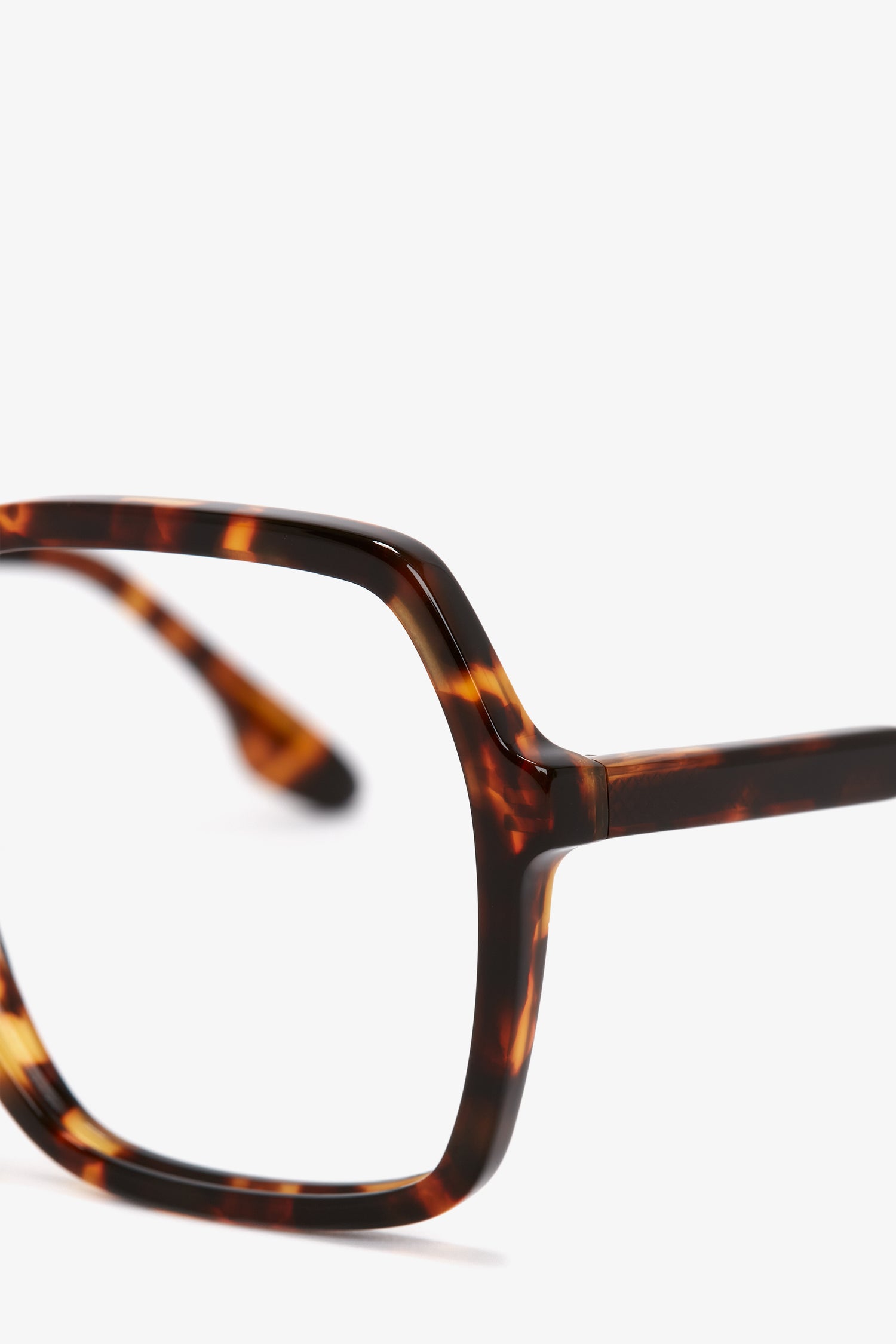 Close-up of the upper half of a Guilloche Frame Opticals In Dark Havana eyeglass frame from the Victoria Beckham collection, focusing on the right lens and temple hinge.